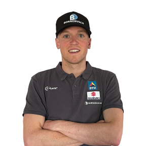 Ein männlicher Sportler mit Baseballcap schaut für ein Portrait mit den Armen vor der Brust verschränkt in die Kamera