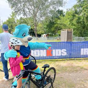 Das Maskottchen Trinity mit Kind und Fahrrad