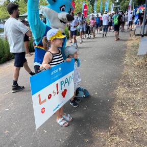 Das Maskottchen Trinity mit Kind und Banner