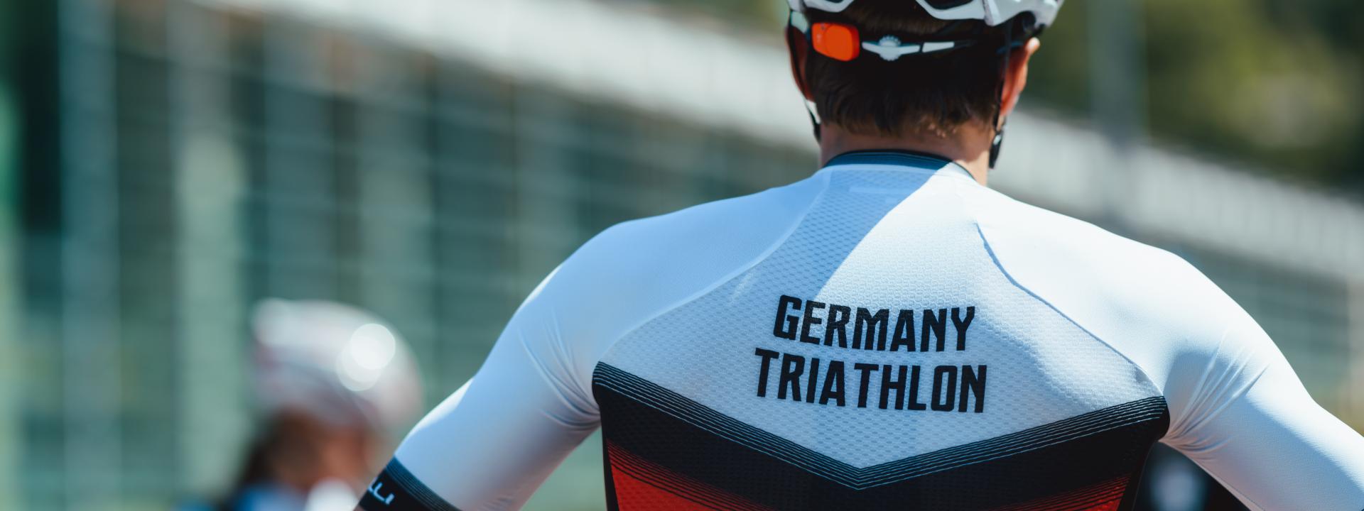 Ein Triathlet in einem Radtrikot in den Deutschlandfarben, auf dem "Germany Triathlon" steht.