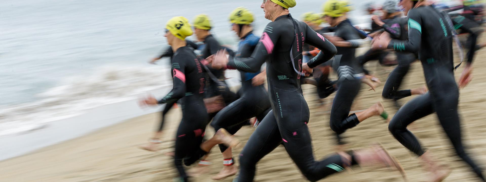 Frauen in einem Neoprenanzug rennen ins Meer
