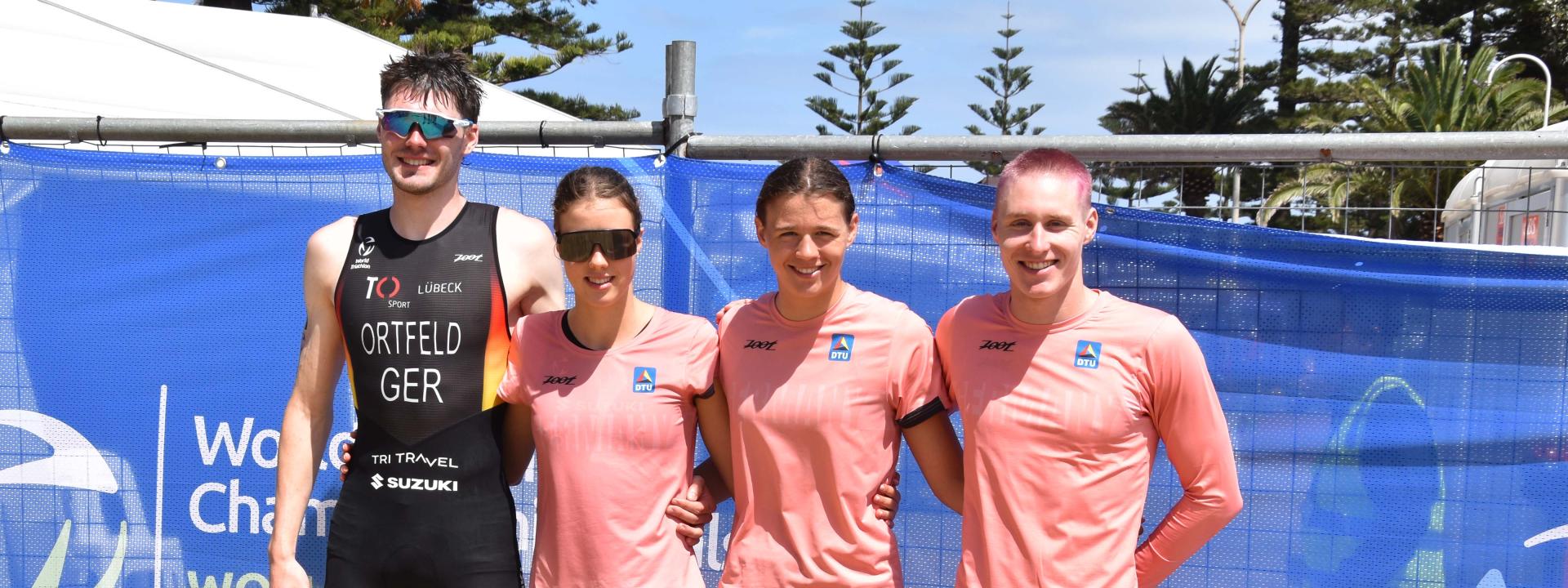 Vier junge Triathleten stehen nebeneinander und lächeln