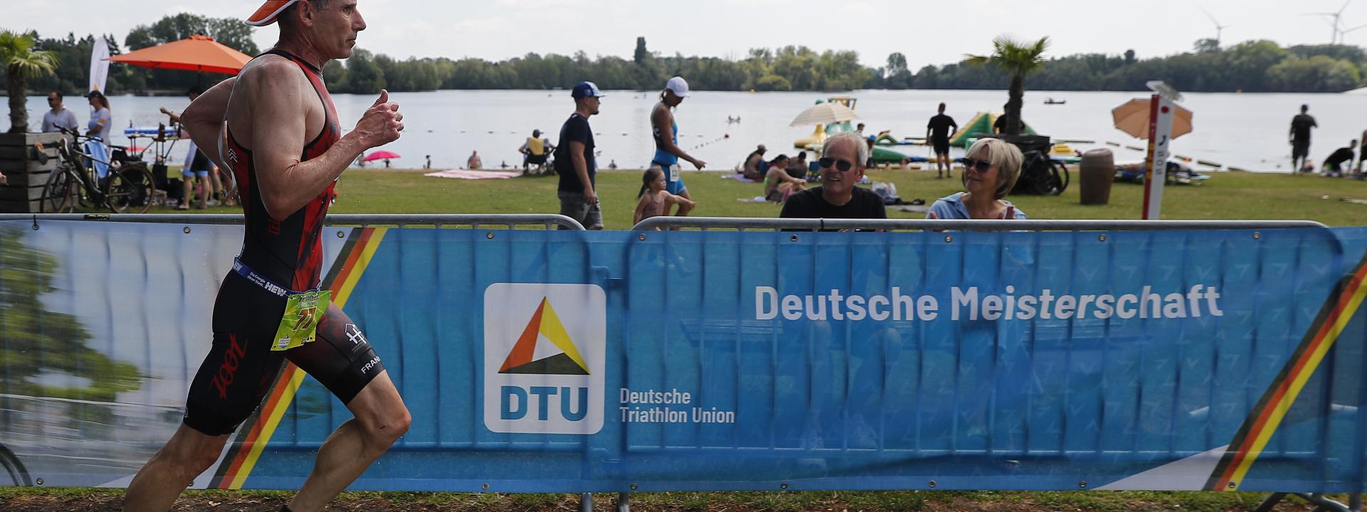 Ein Läufer läuft vor einem Banner vorbei, auf dem Deutsche Meisterschaften steht