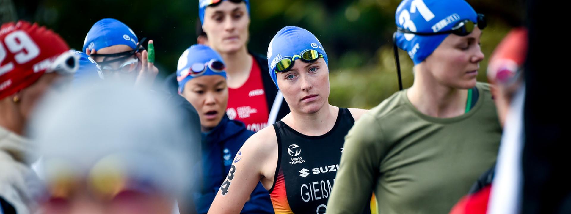 Athleten mit blauen Badekappen auf dem Kopf warten