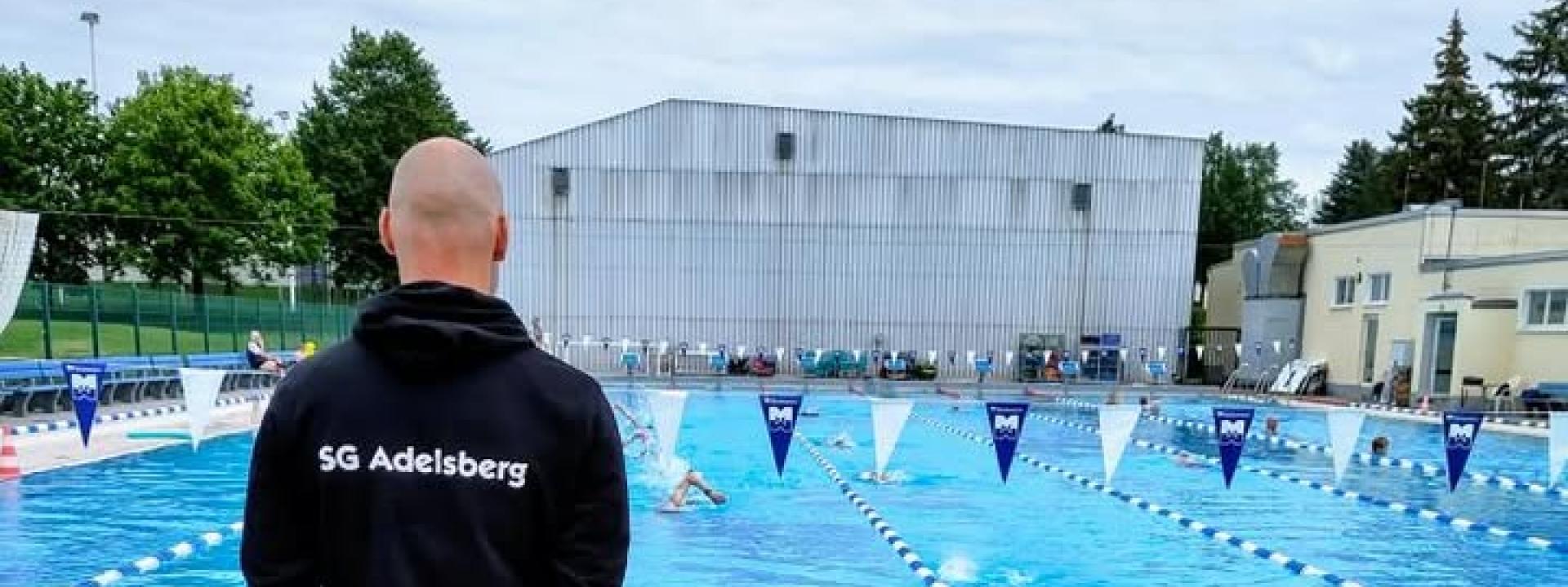 Trainer steht am Beckenrand