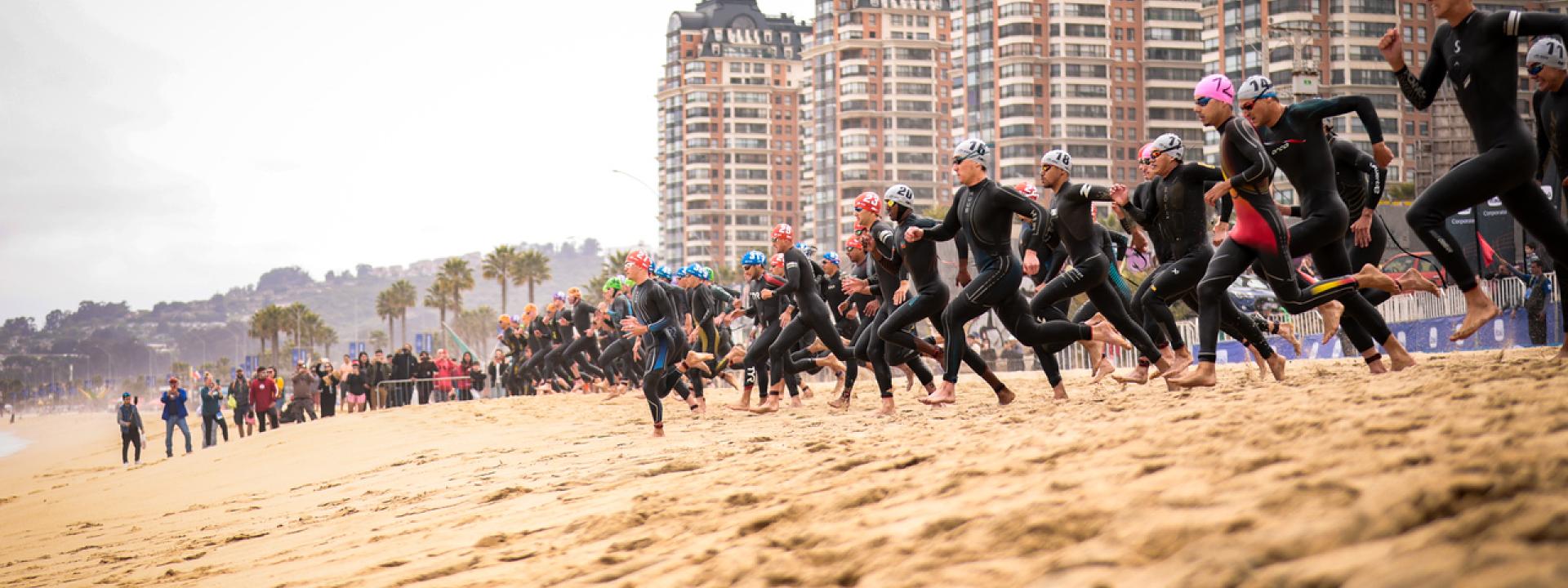 Mehrere Menschen im Neopren rennen ins Meer