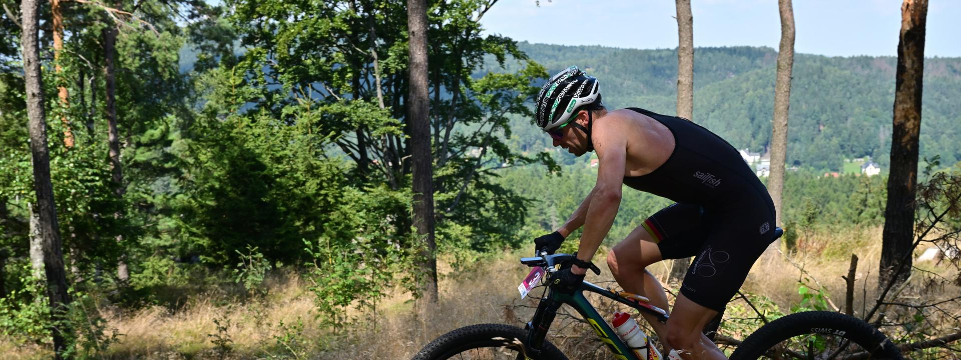 Ein Athlet fährt auf einem Mountainbike durch einen Wald