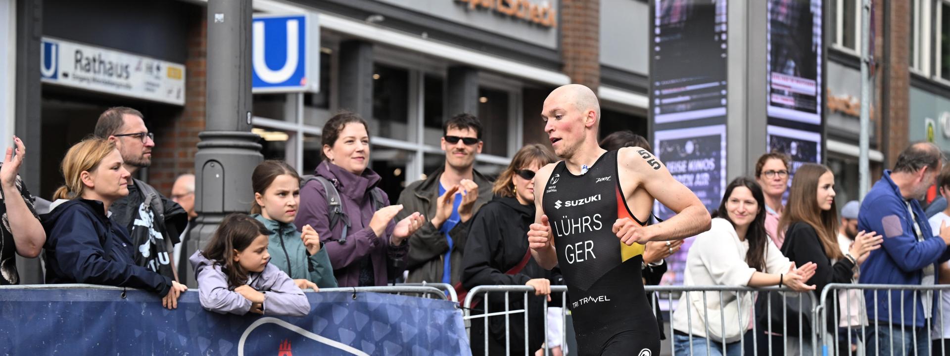 Lasse Lührs läuft im Deutschland-Einteiler an einer ganzen Reihe von zuschauern vorbei, die hinter der Absperrung gebannt zusehen und anfeuern