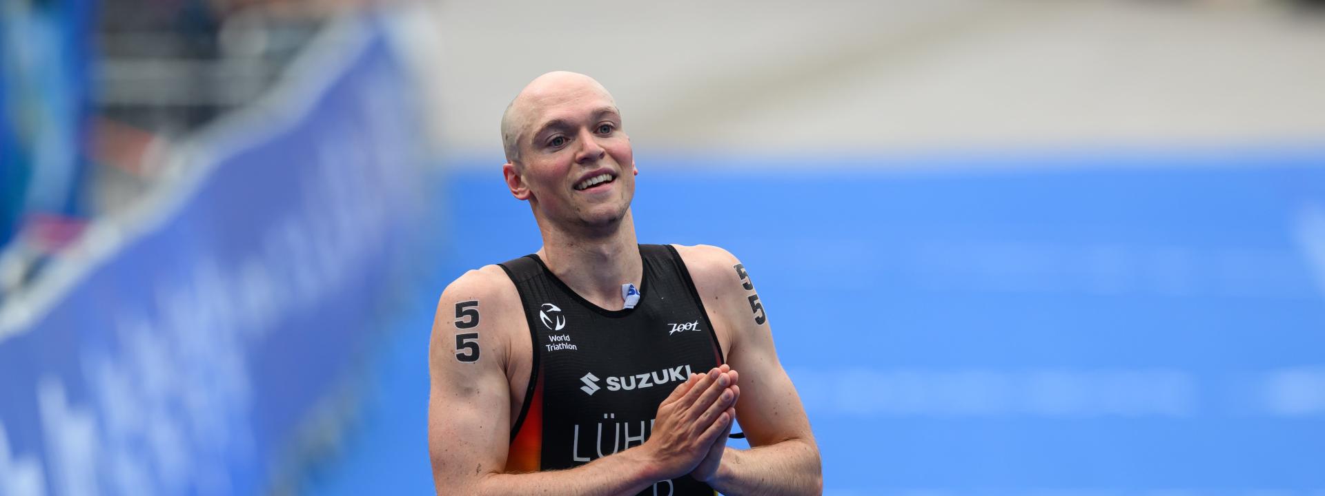 Ein Triathlet faltet im Zielbereich dankend die Hände für das Publikum