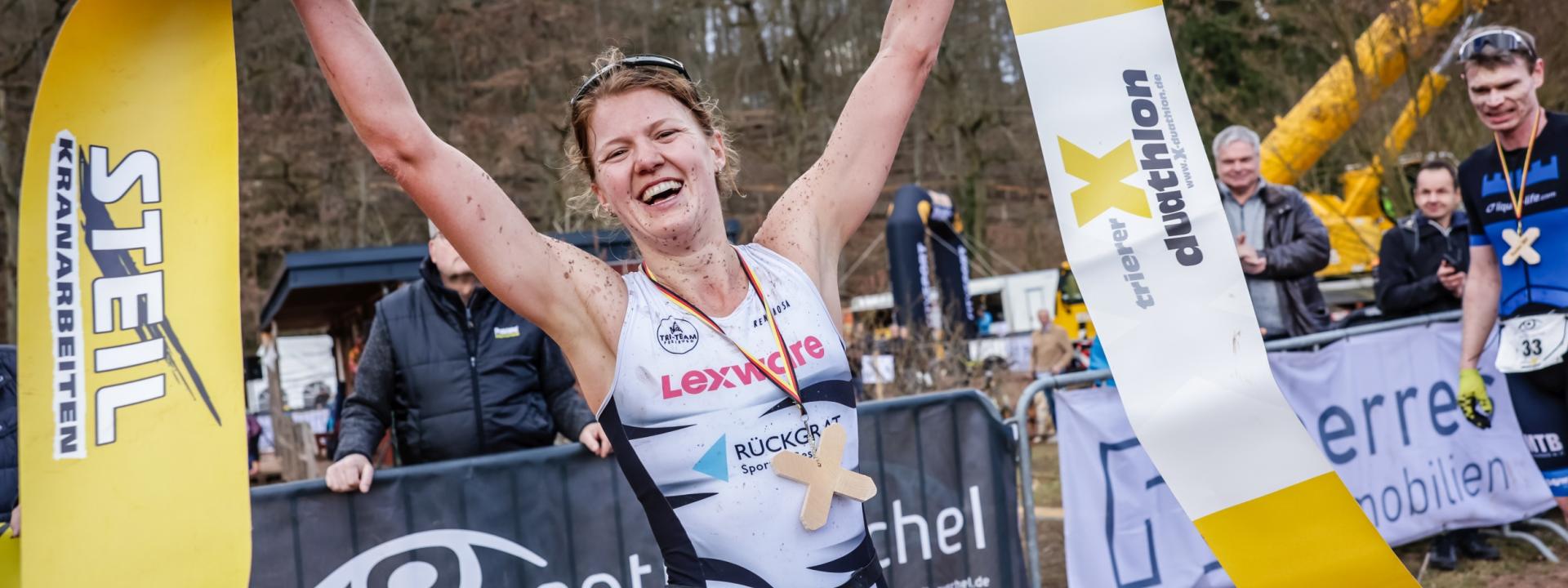 Eine Duathletin jubelt im Ziel mit dem Zielband in der Hand über ihren Sieg