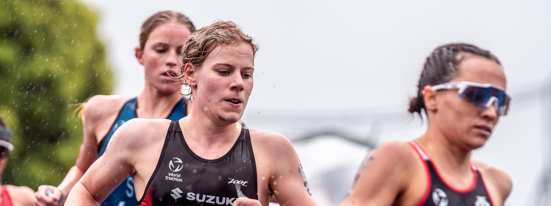 Eine deutsche Triathletin läuft gemeinsam mit zwei anderen Triathletinnen im Regen