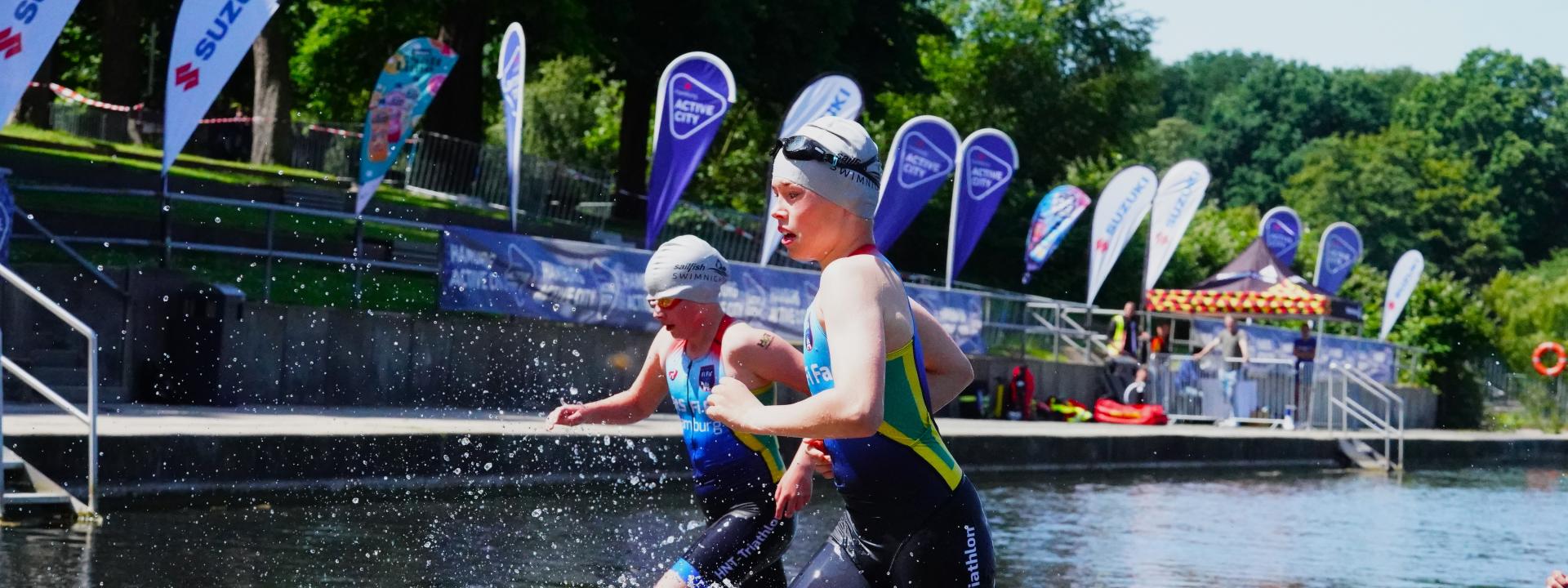 zwei Jungs laufen aus dem Wasser, im Hintergrund die Suzuki Fahnen