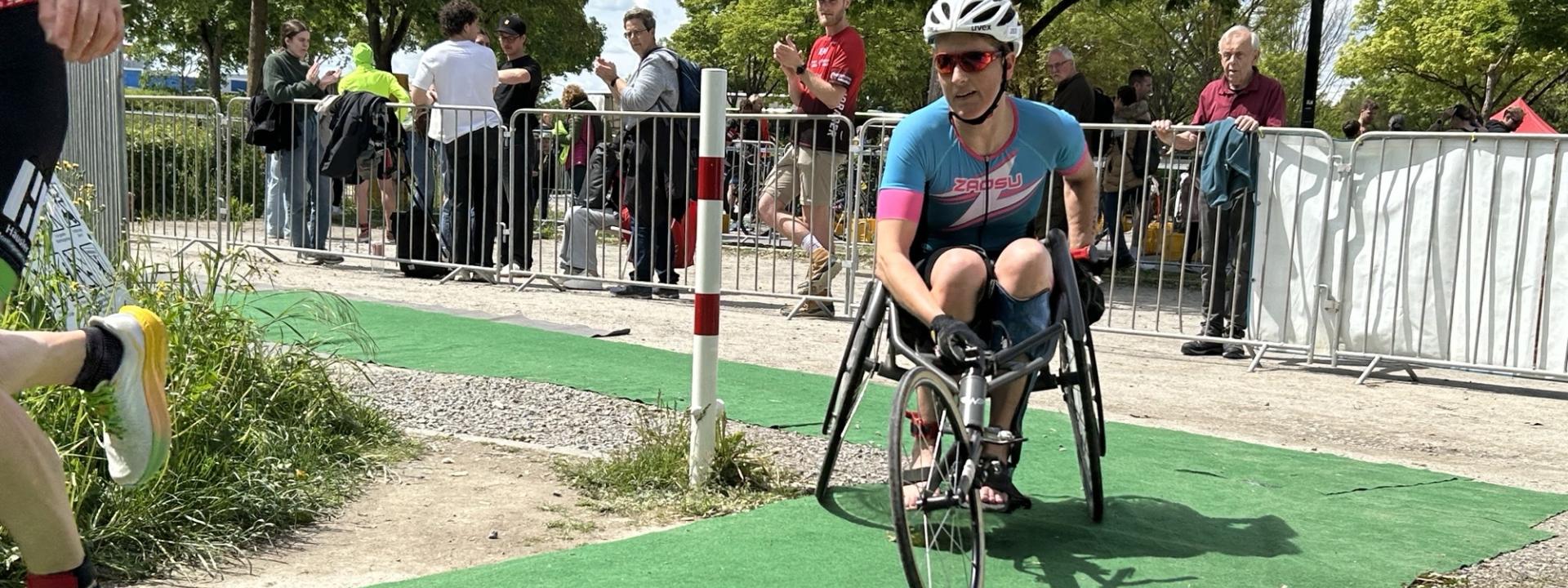 Eine Para Triathletin im Rollstuhl fährt eine Rechtskurve