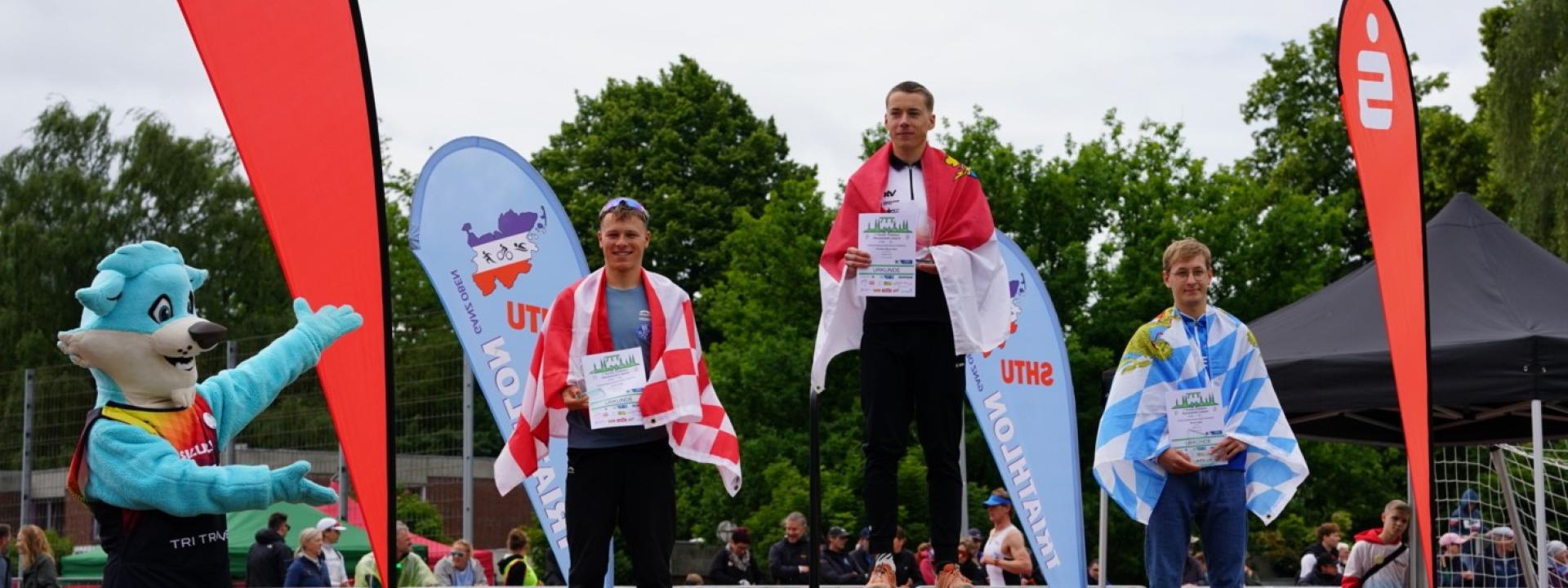 Junioren auf dem Podium und Trinity das Maskottchen 