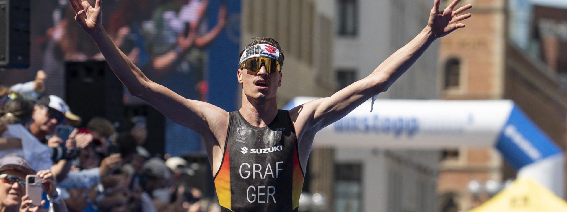 Ein männlicher Triathlet jubelt auf der Zielgeraden eines Triathlons