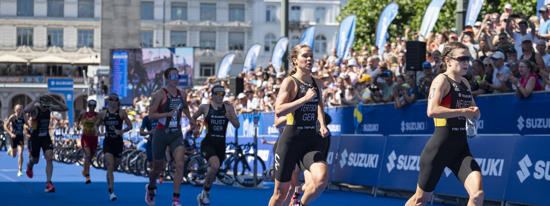Mehrere Frauen laufen bei einem Triathlon aus der Wechselzone