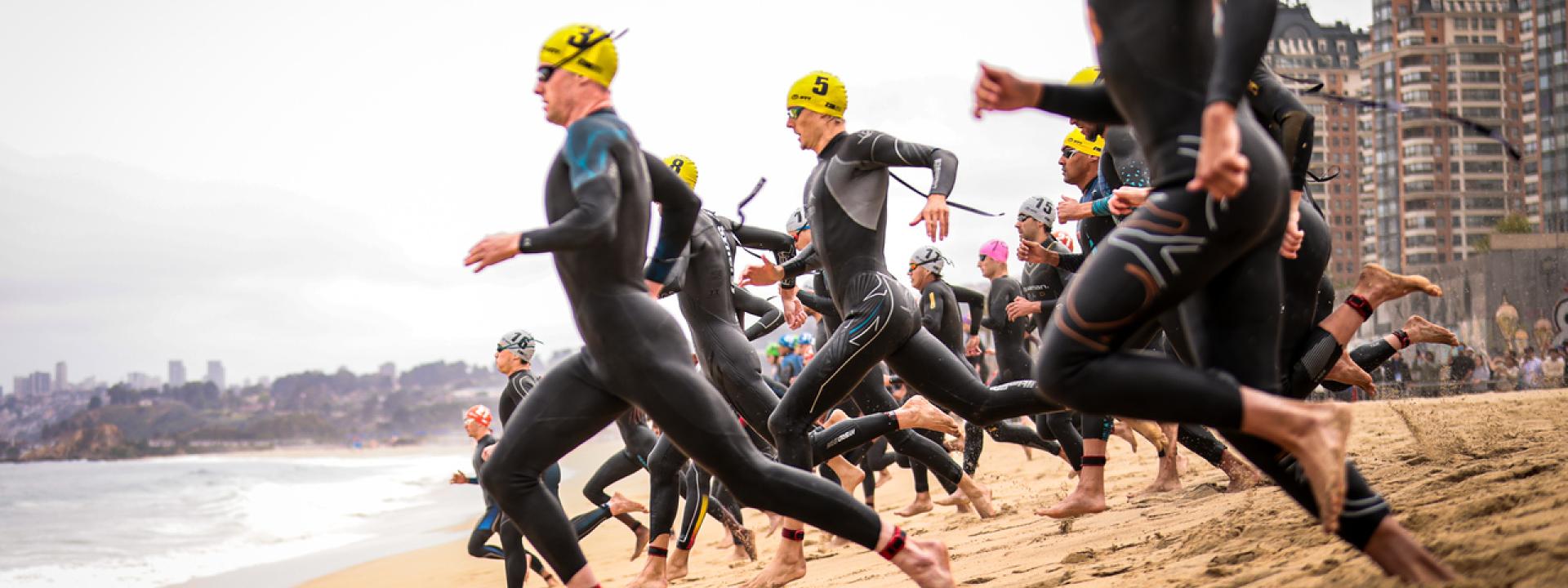 Männer rennen über den Strand ins Meer