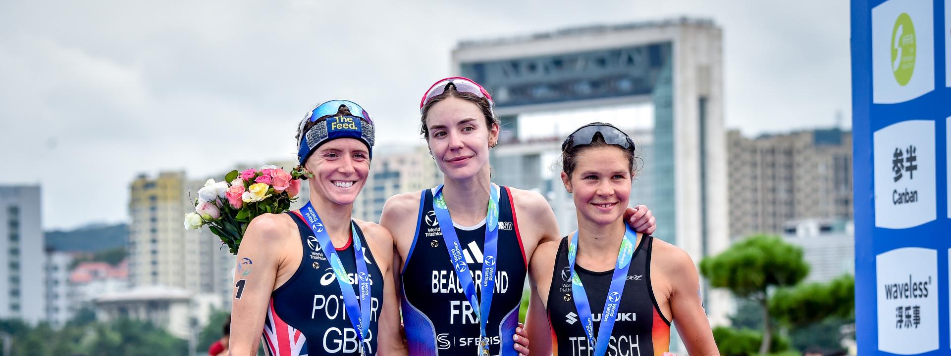 Drei Triathletinnen posieren auf dem Podium für ein Portrait der Top-3 des Rennens