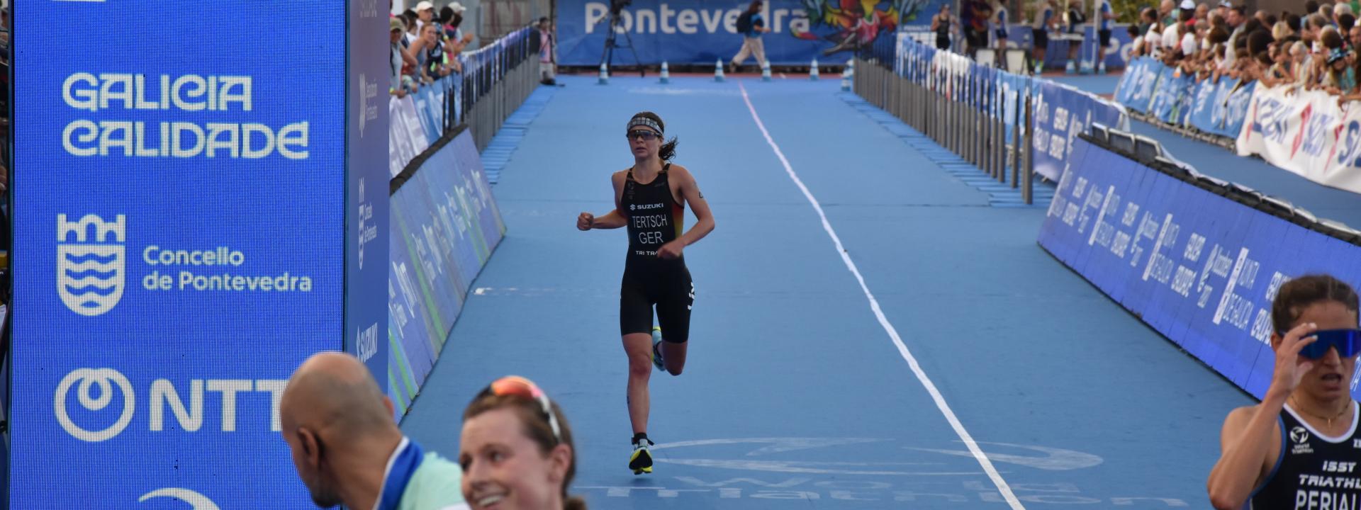 Eine Triathletin läuft ins Ziel, vor ihr sind bereits weitere Athletinnen im Zielbereich angekommen