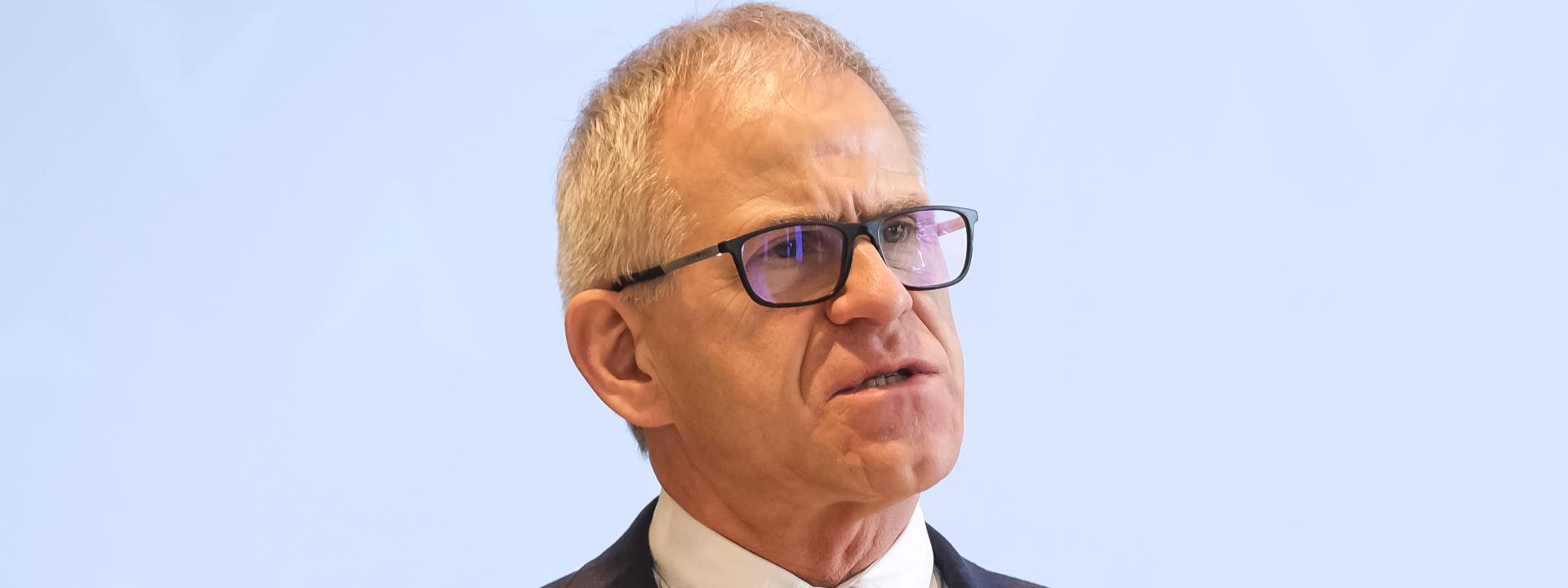 Ein Portrait eines älteren Mannes in Anzug, der eine Brille trägt
