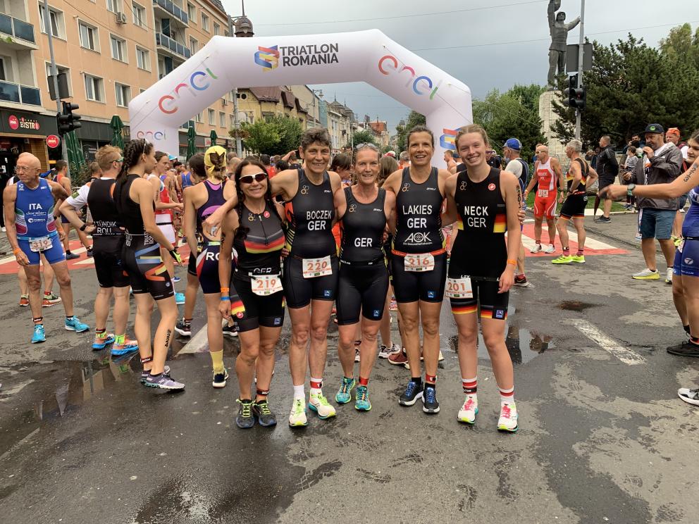 Gruppenbild von Triathleten vor einem Zielbogen