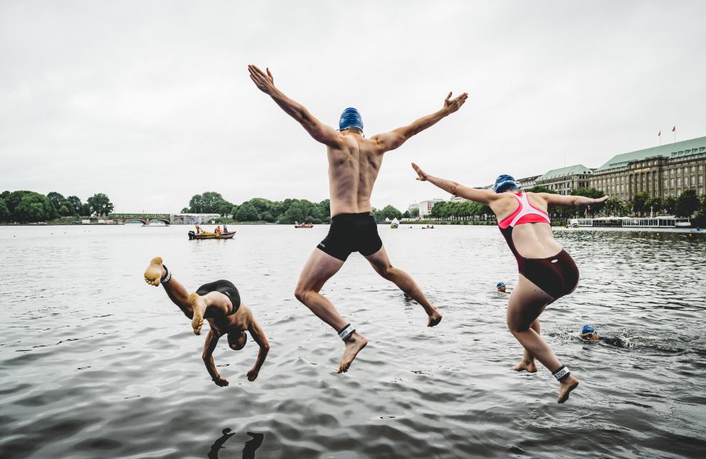 Triathletinnen und Triathleten springen ins Wasser 