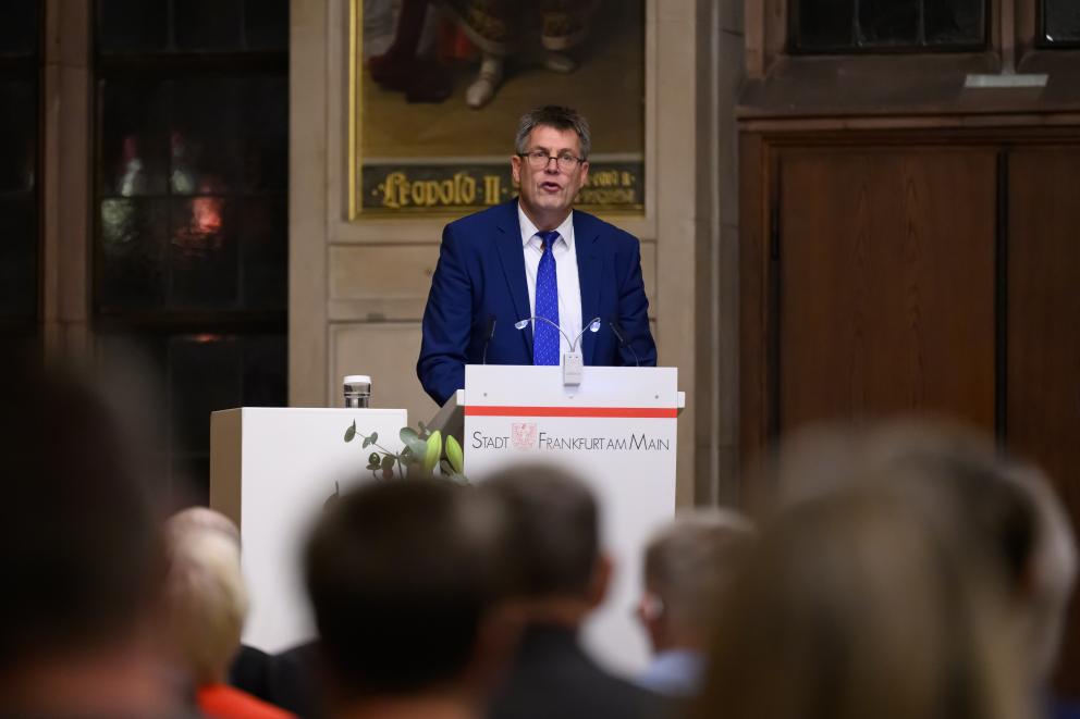 Ein Mann steht am Rednerpult und spricht zu einem Publikum