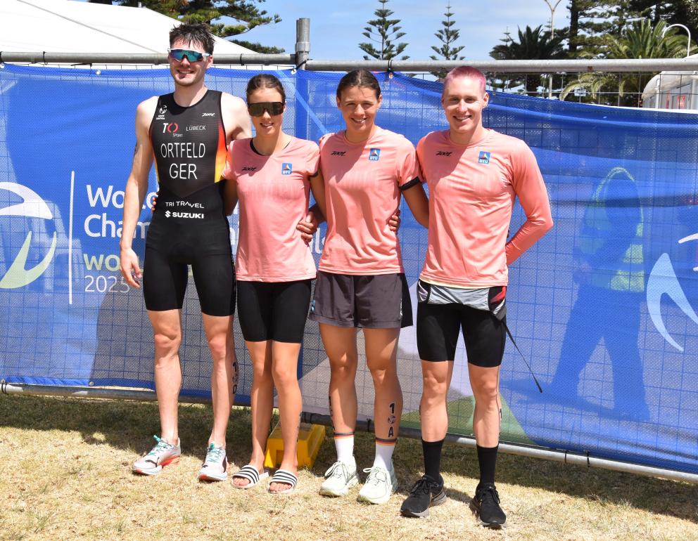 Vier junge Triathleten stehen nebeneinander und lächeln