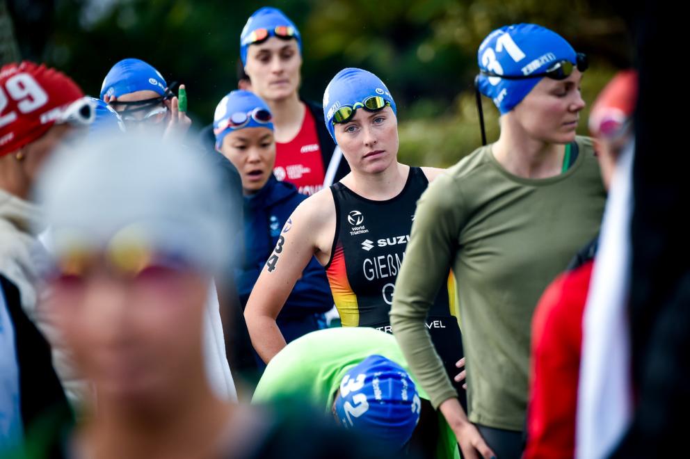 Athleten mit blauen Badekappen auf dem Kopf warten