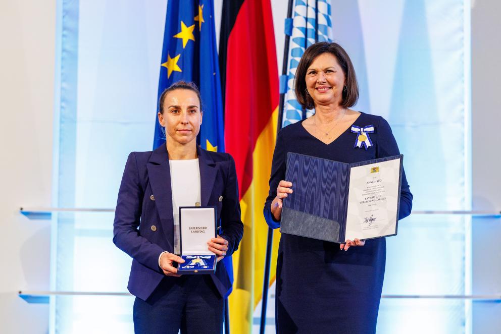 Eine geehrte Preisträgerin präsentiert gemeinsam mit ihrer Laudatorin eine Urkunde und eine Medaille