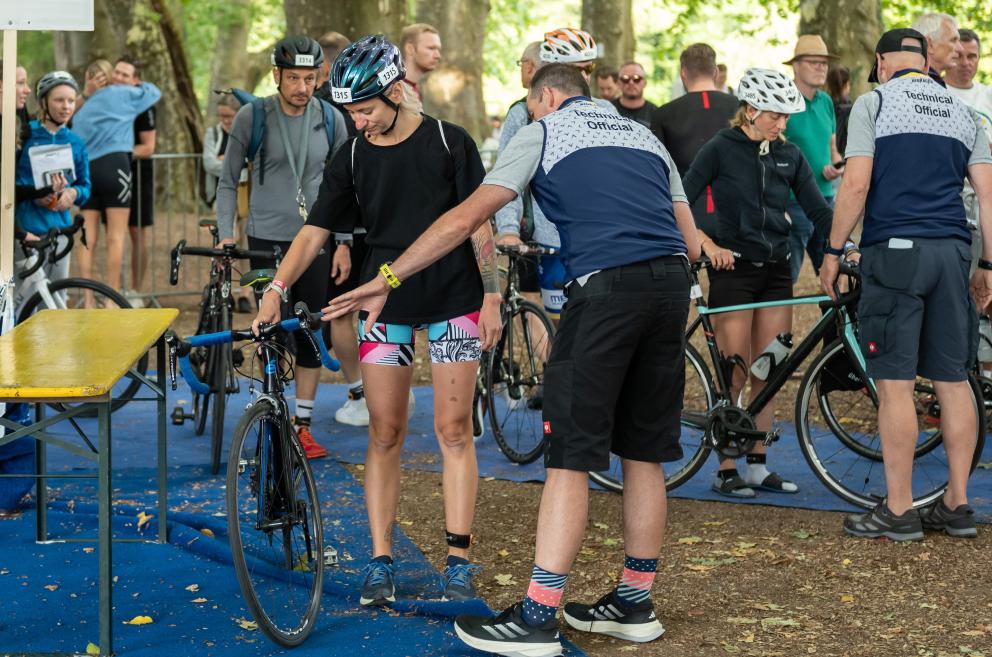 Check-In bei einem Triathlon Frau mit Fahrrad und Technical Official