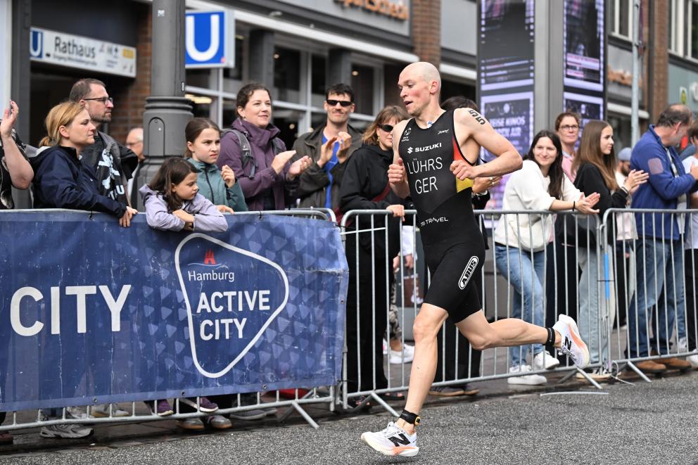 Lasse Lührs läuft im Deutschland-Einteiler an einer ganzen Reihe von zuschauern vorbei, die hinter der Absperrung gebannt zusehen und anfeuern
