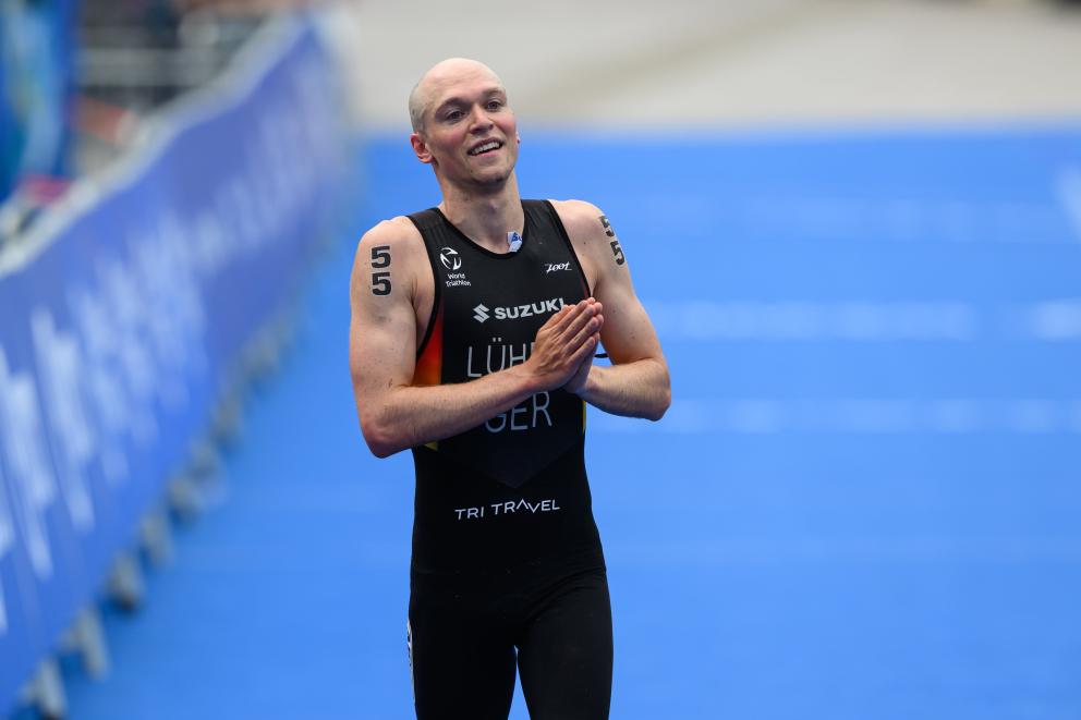 Ein Triathlet faltet im Zielbereich dankend die Hände für das Publikum