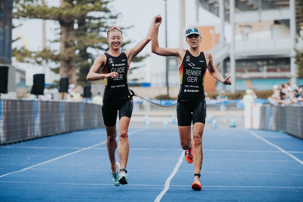Zwei Triathletinnen überqueren gemeinsam, sich an der Hand haltend die Ziellinie