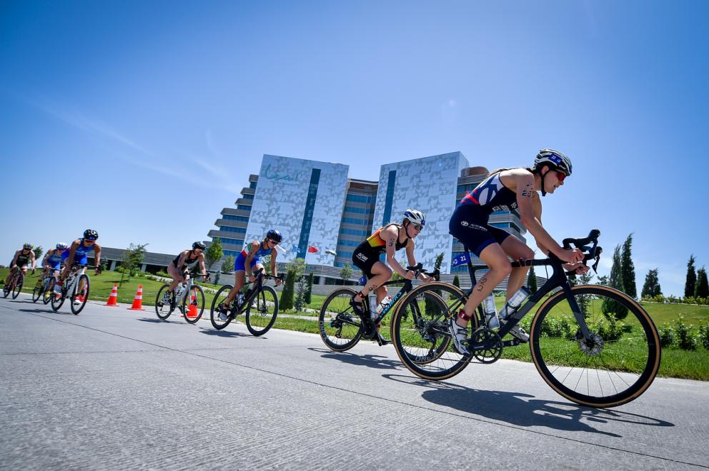 Mehrere Triathletinnen fahren auf einer Straße zusammen hintereinander Rad