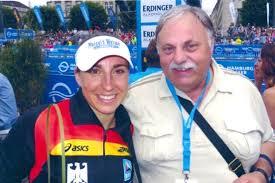 Hein Rüger hält legt den Arm um Athletin und beide lächeln in die Kamera