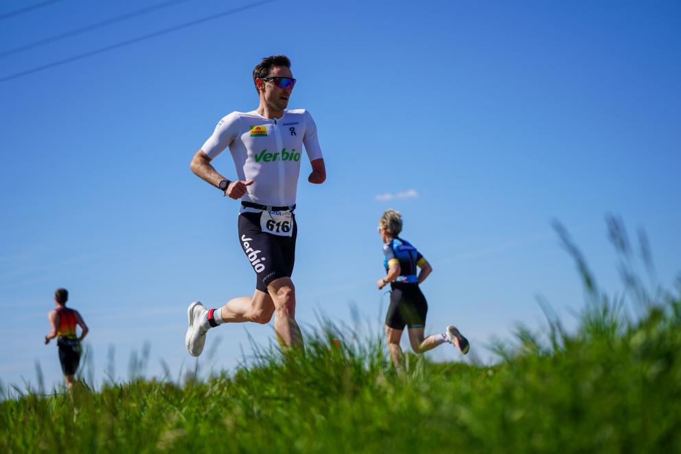 Para Triathlet beim Laufen mit grüner Wiese und blauem Himmel