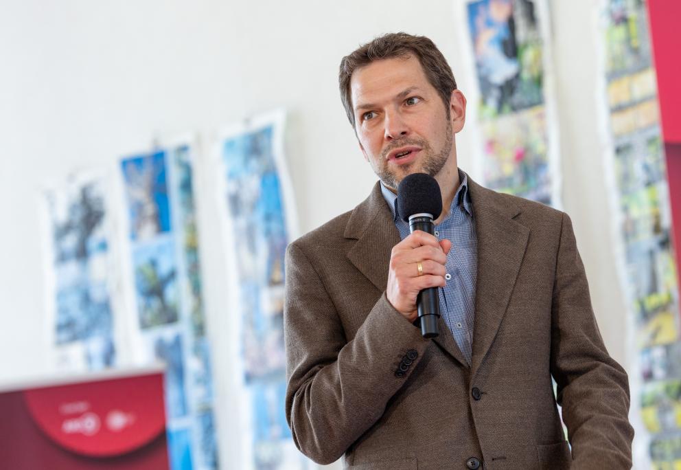 Matthias Zöll spricht während der Pressekonferenz über Die Finals. In der Hand hält er ein Mikrofon.