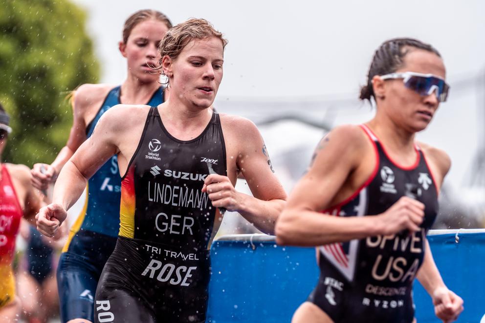 Eine deutsche Triathletin läuft gemeinsam mit zwei anderen Triathletinnen im Regen
