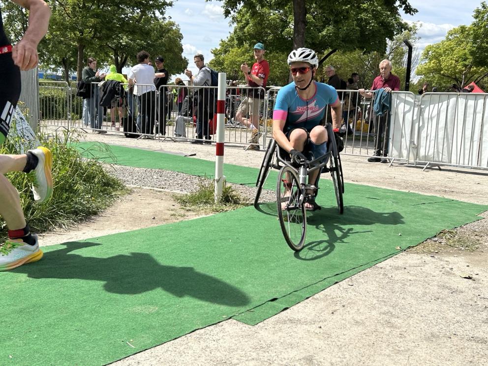 Eine Para Triathletin im Rollstuhl fährt eine Rechtskurve