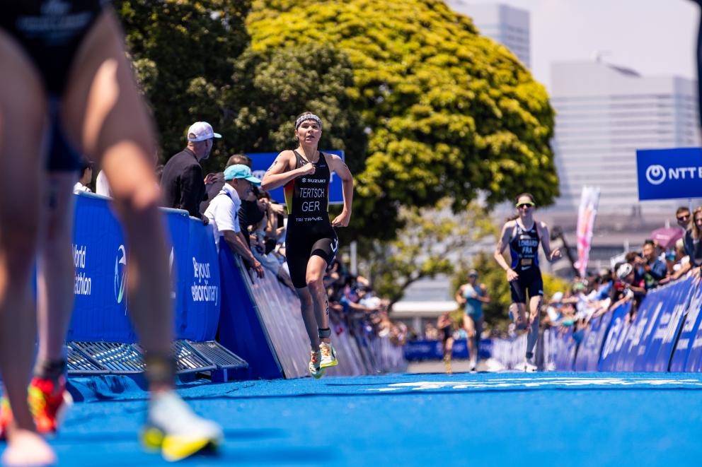 Eine Triathletin sprintet auf dem Zielteppich Richtung Ziellinie