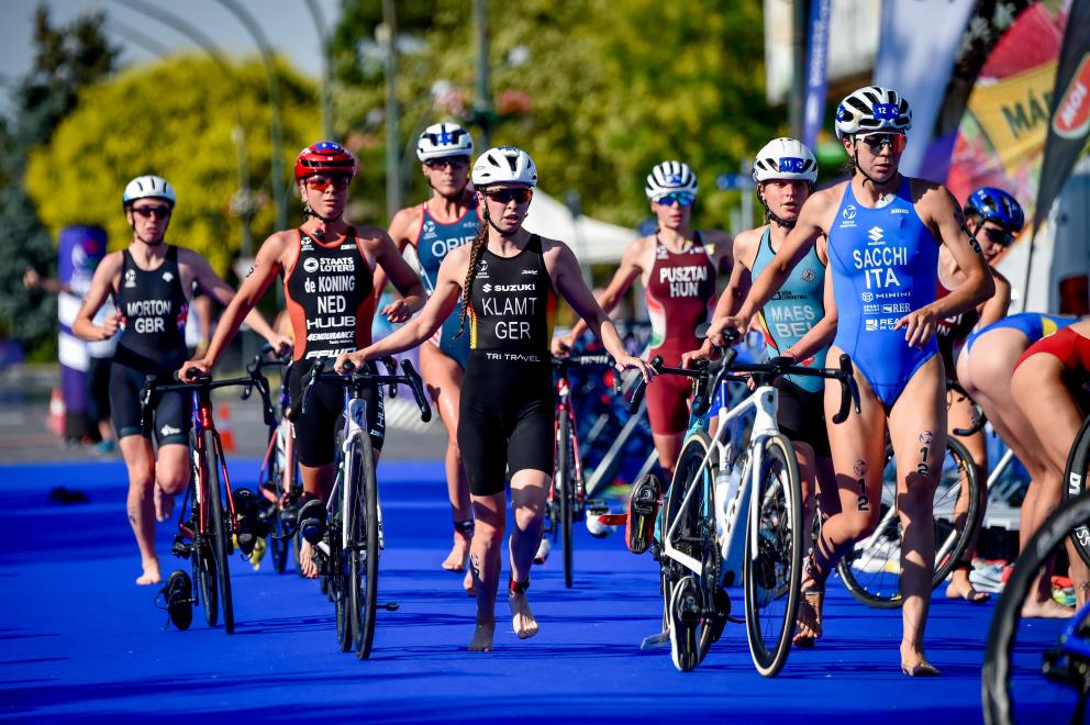 Triathletinnen laufen mit Rädern in die Wechselzone bei einem internationalen Rennen
