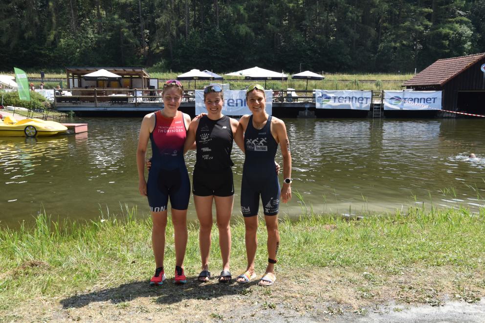 Drei Athletinnen stehen auf einer Wiese