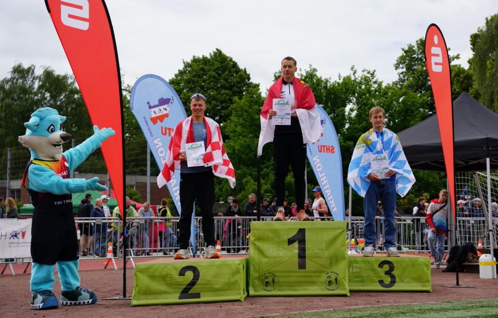Junioren auf dem Podium und Trinity das Maskottchen 