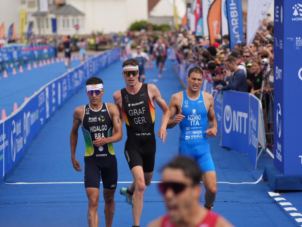 Mehrere Triathleten laufen im Sprint in das Ziel eines Rennens