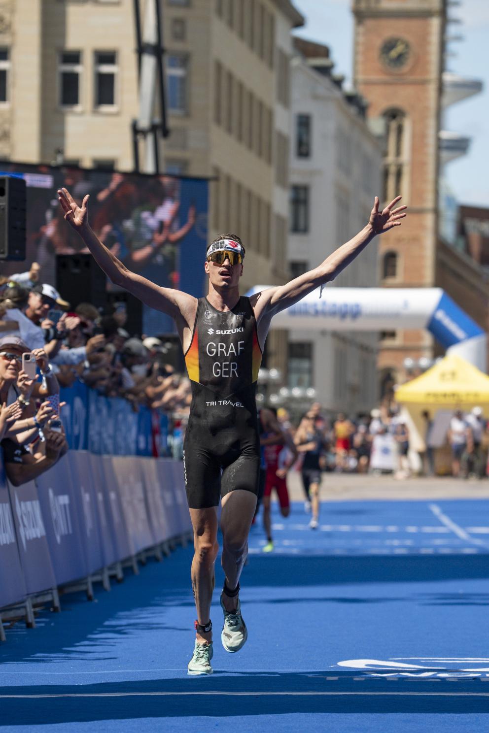 Ein männlicher Triathlet jubelt auf der Zielgeraden eines Triathlons