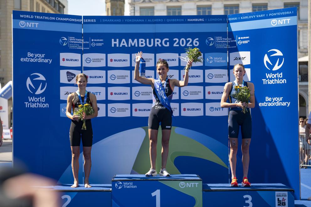 Drei Frauen stehen auf einem Podium nach einem Triathlon