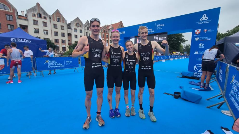 Zwei Frauen und zwei Männer posieren freudestrahlend nach EM-Bronze im Zielbereich des Triathlon-Kurses