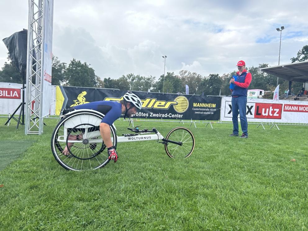 Ein Rollstuhl-Sportler fährt mit dem Rollstuhl über eine Wiesenstrecke