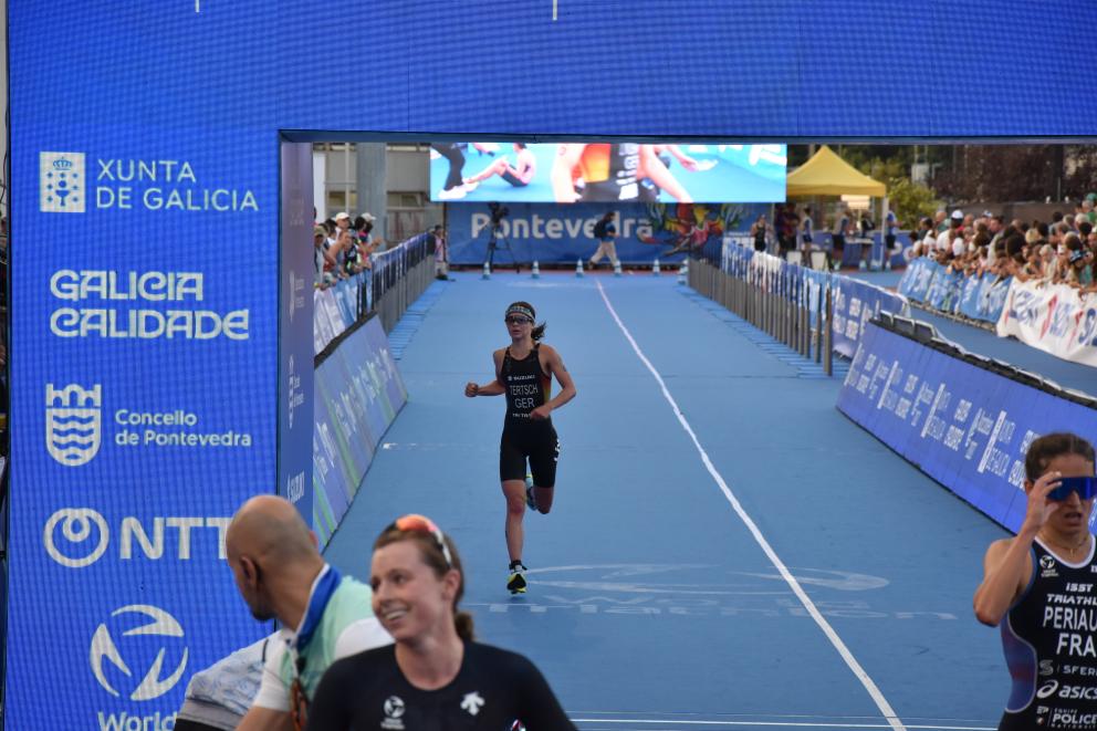 Eine Triathletin läuft ins Ziel, vor ihr sind bereits weitere Athletinnen im Zielbereich angekommen